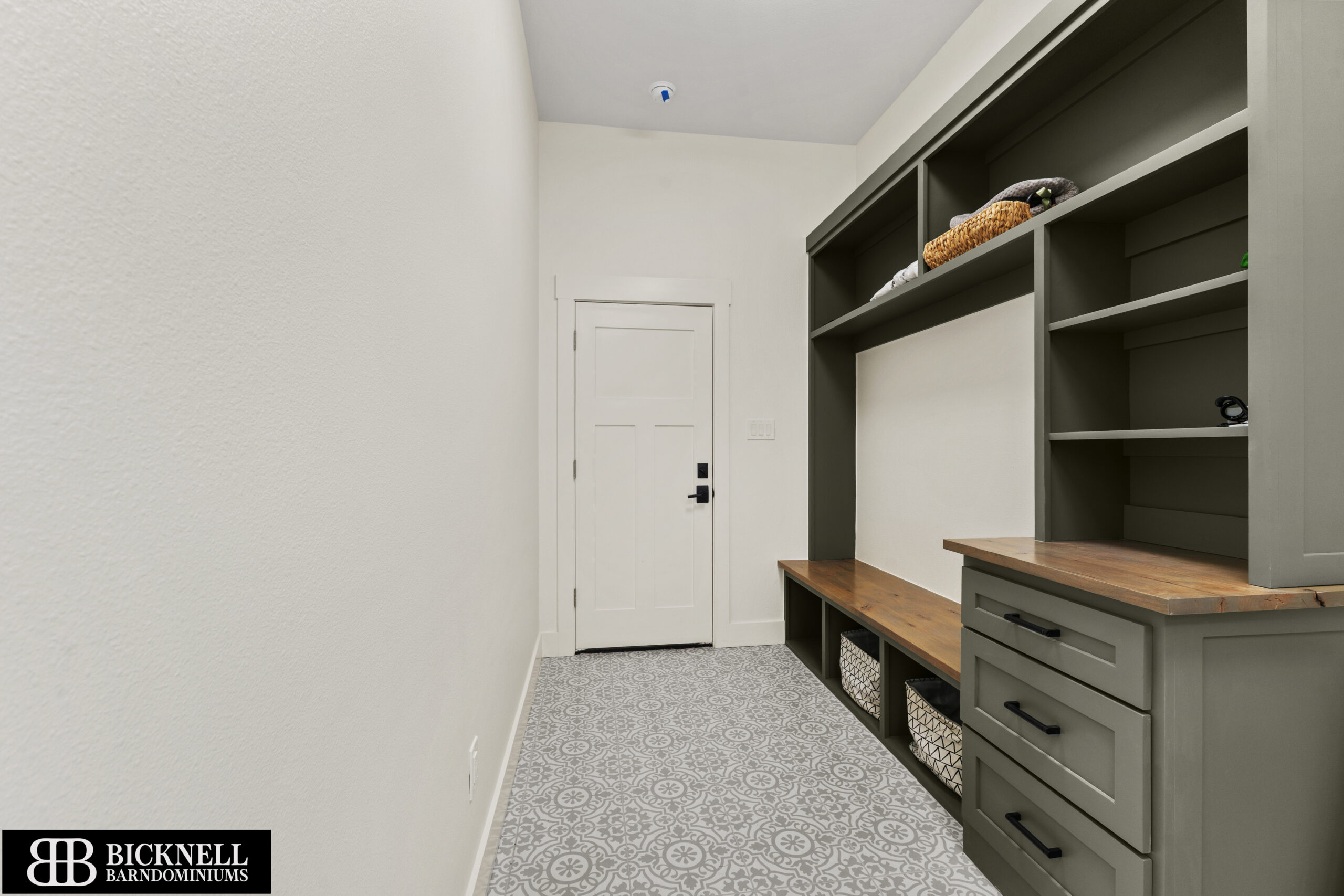 Walk-in closet with gray built-in shelving, drawers, and a wooden countertop beneath open storage bays.",