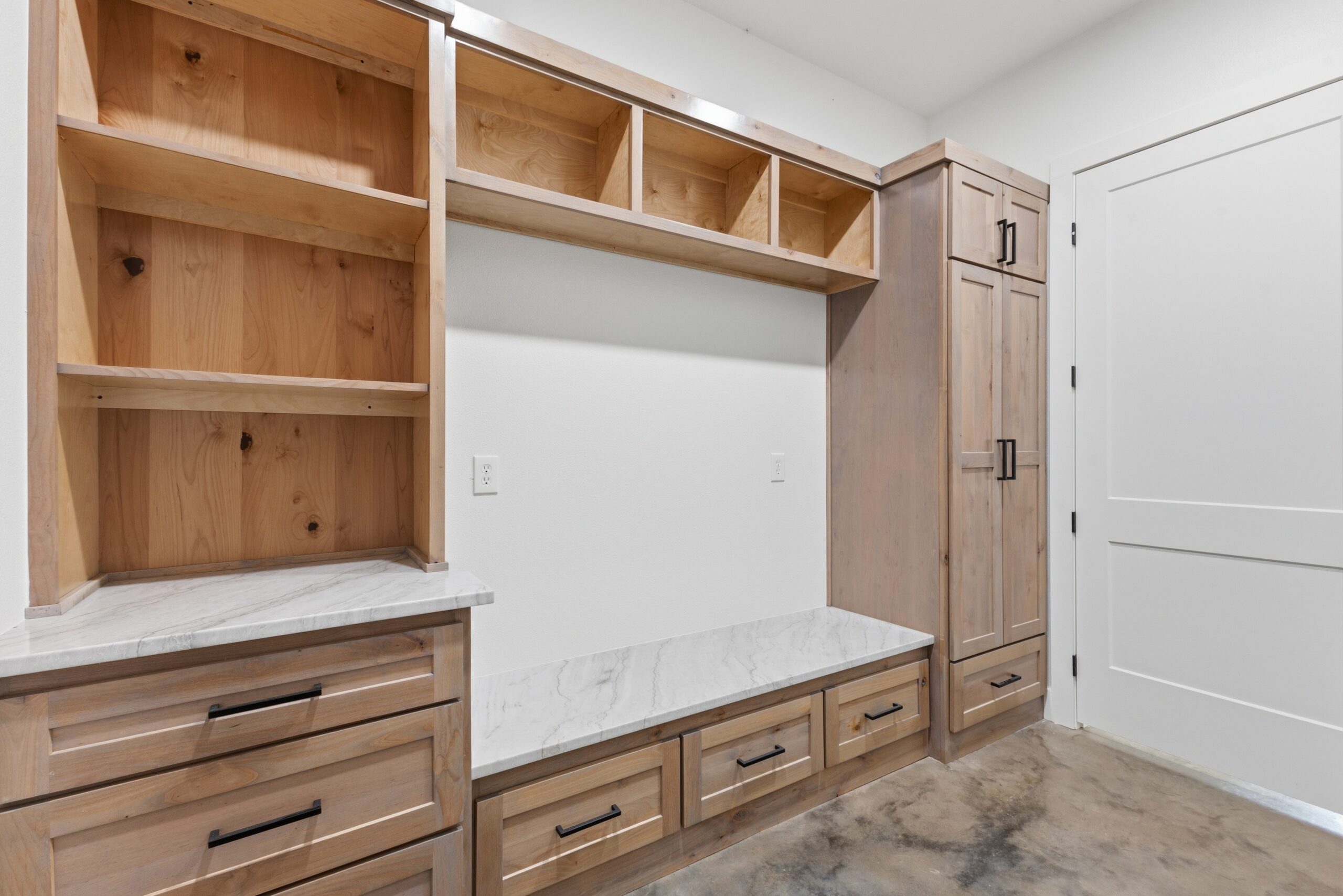 Wooden kitchen cabinetry with open cubby shelves above a marble countertop.