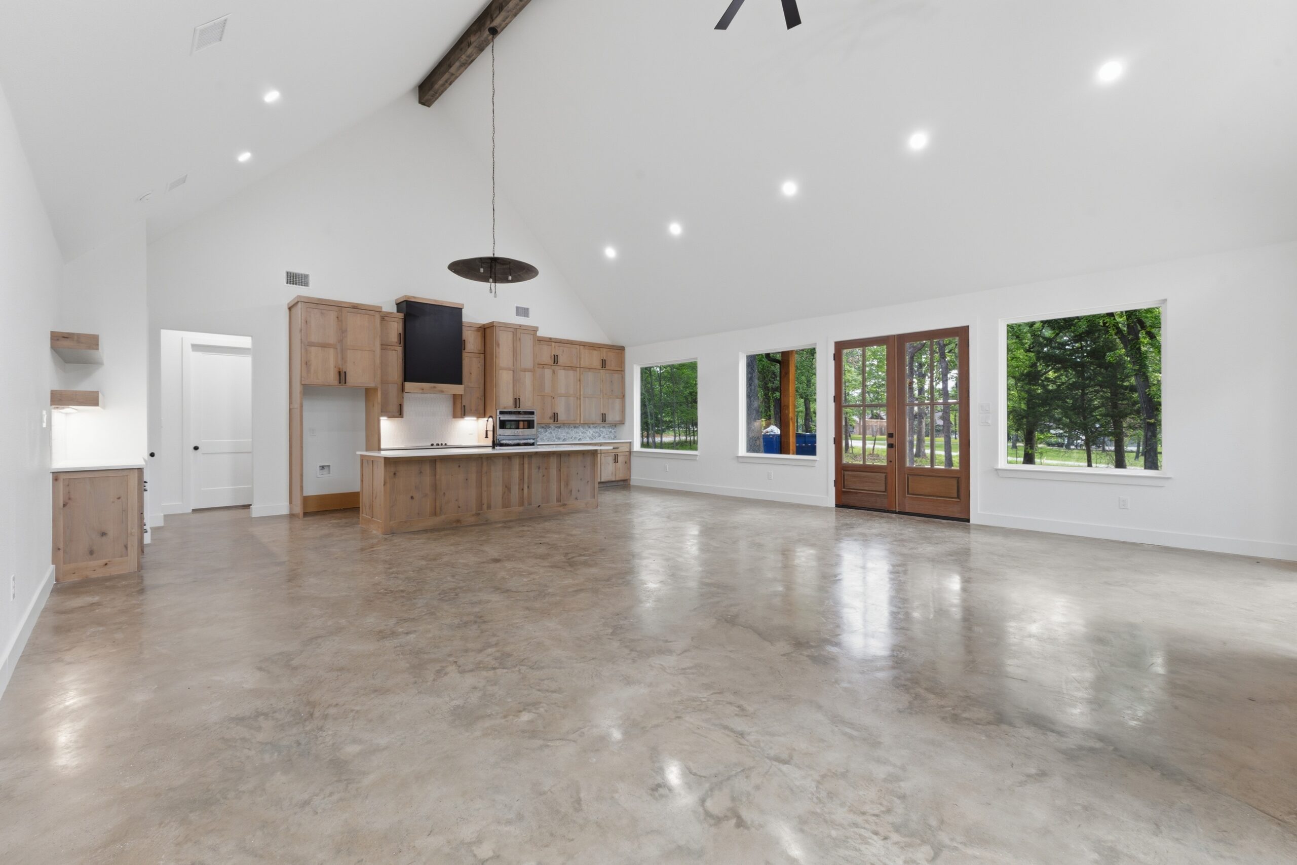 Bright open-concept kitchen with wooden cabinets, an island, stainless appliances, and large windows/doors offering garden views