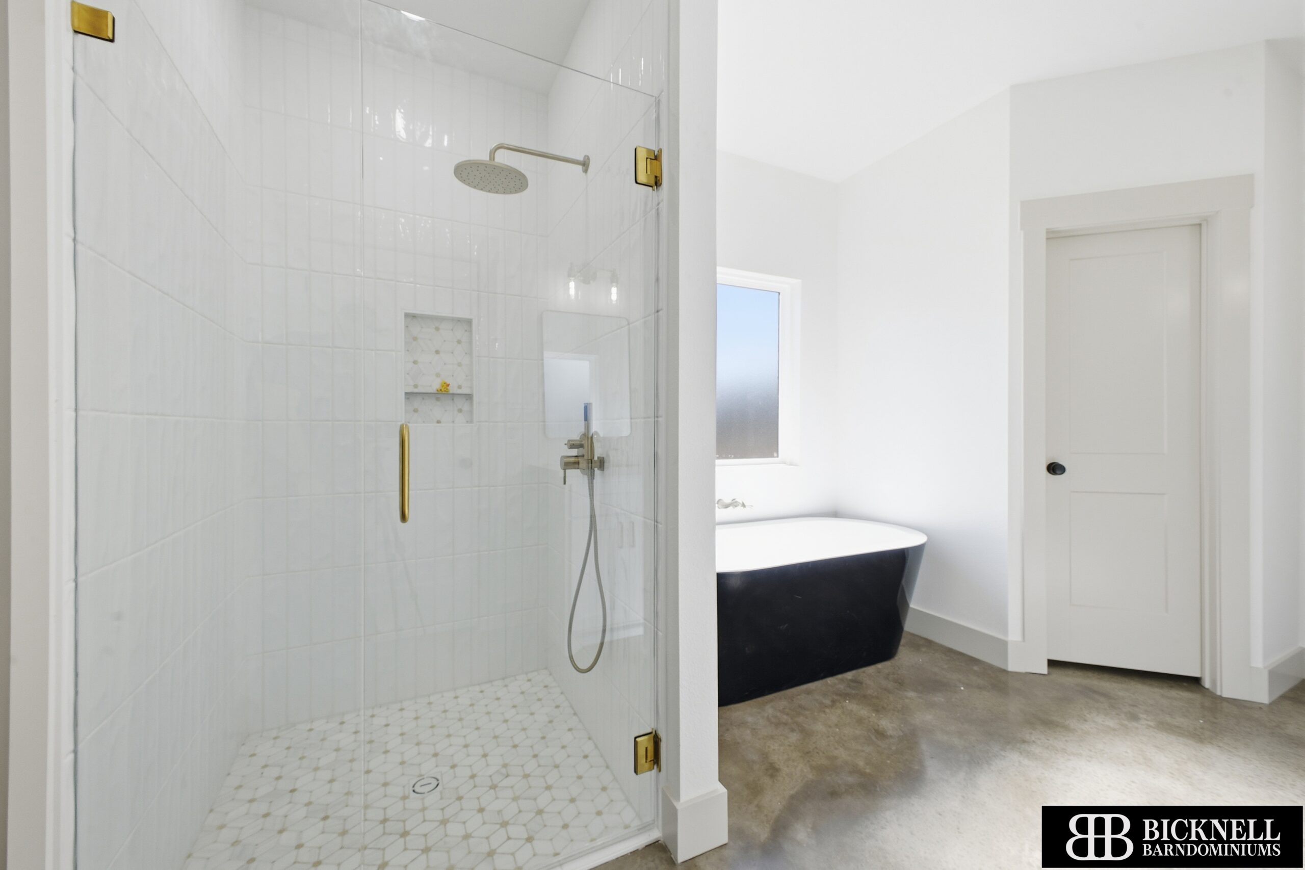 Modern bathroom with a glass-enclosed shower, freestanding bathtub, white walls, and concrete floor. Bicknell Barndominiums logo is in the bottom right corner.